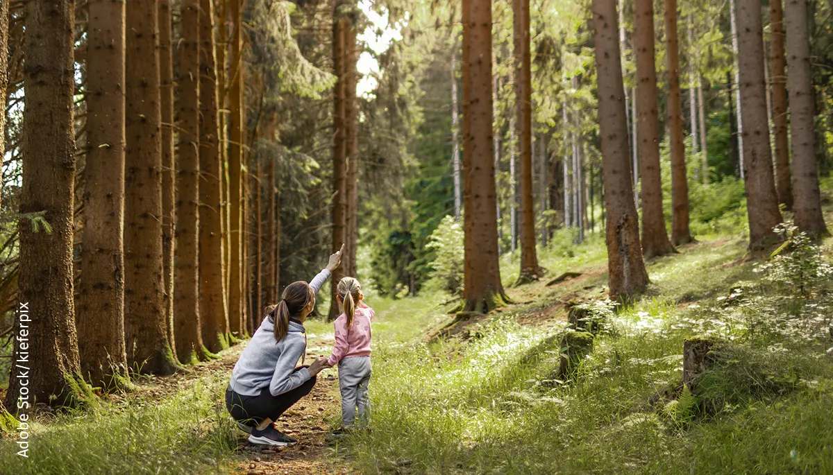 Woman shows a girl something in the forest